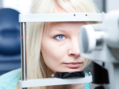optometry concept - pretty young woman having her eyes examined